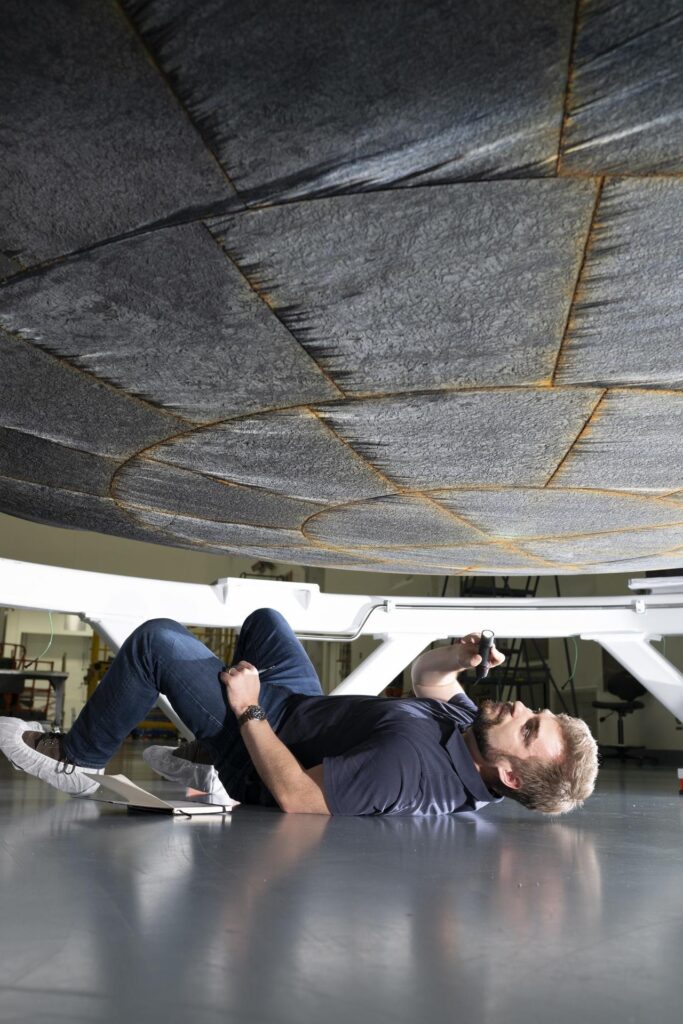 An engineer from NASA Ames inspects the Artemis II heat shield at Kennedy's Multi-Purpose Payload Facility
