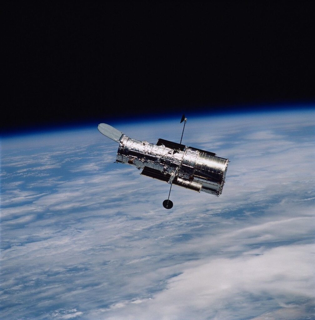The Hubble Space Telescope orbiting above the clouds of Earth