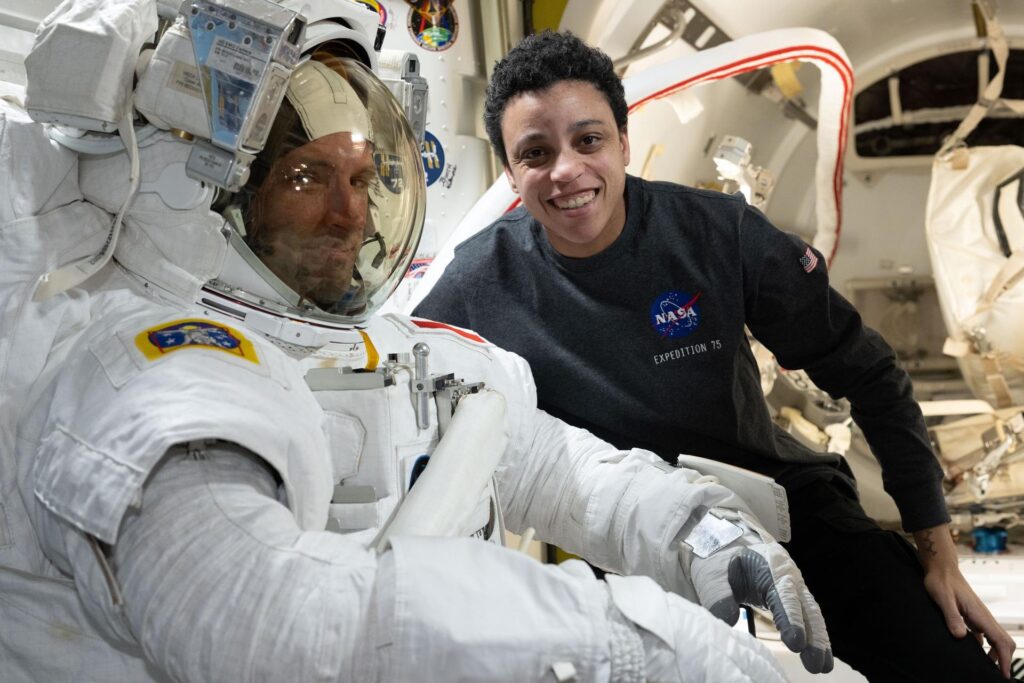 Expedition 75 flight engineers Joshua Kutryk and Jessica Watkins pose inside the Quest airlock during a spacesuit fit check