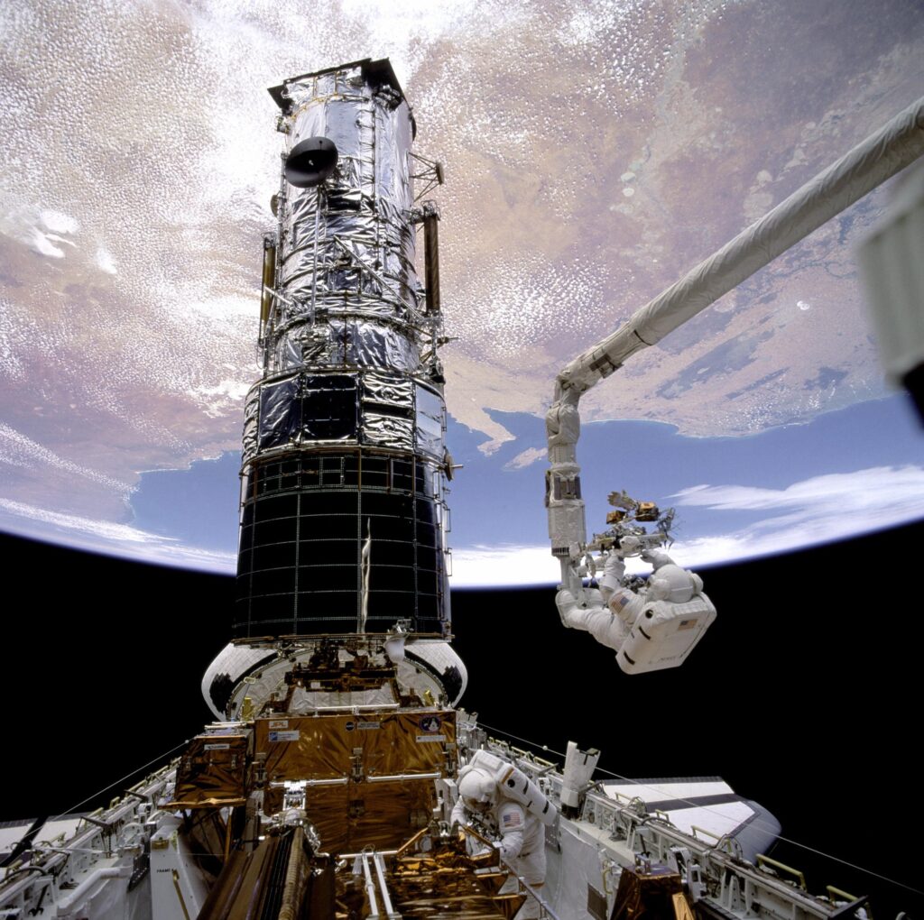 Astronaut F. Story Musgrave on the Space Shuttle Endeavour's robotic arm raised toward Hubble during its 1993 first servicing mission