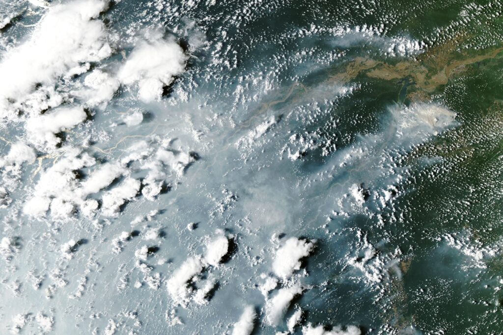 Thick gray smoke partially obscures the Amazon River and surrounding rainforest near Manaus and Santarém.